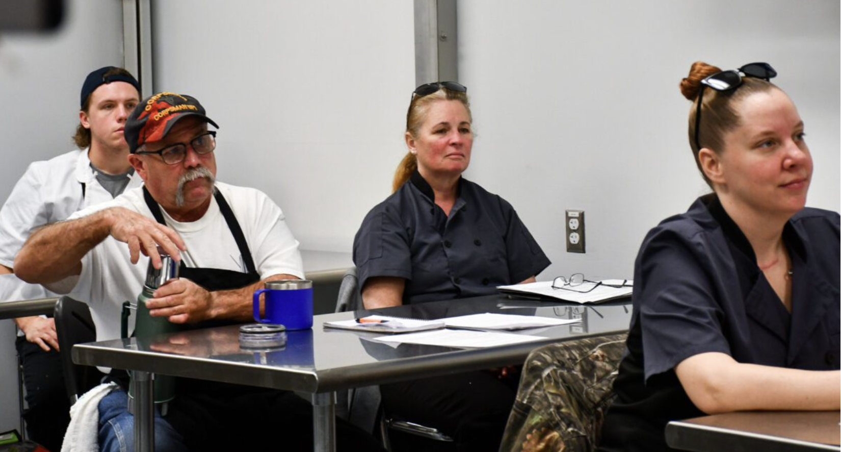 Adult learners sit at desks in a classroom